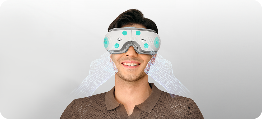 Uśmiechnięty mężczyzna używa białego masażera oczu SKG ES300 z wizualizacją masażu skroni za pomocą dłoni