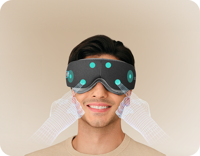 Mężczyzna uśmiecha się, używając szarego masażera oczu SKG ES500, z wizualizacją punktów masujących na twarzy