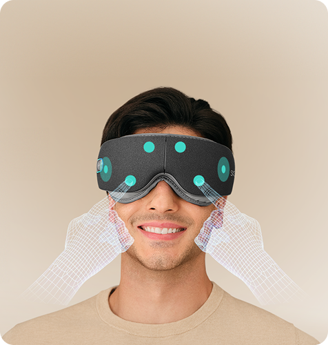 Mężczyzna uśmiecha się, używając szarego masażera oczu SKG ES500, z wizualizacją punktów masujących na twarzy