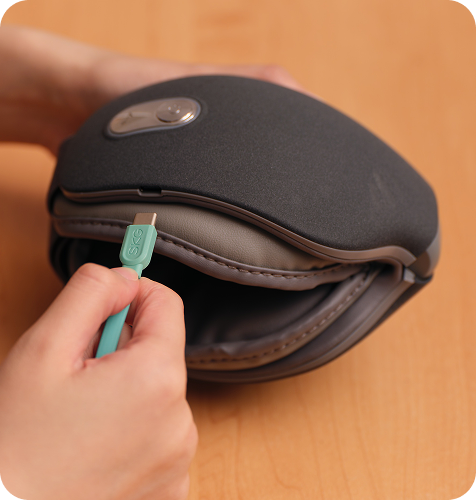 Ładowanie złożonego masażera oczu SKG ES500 w kolorze szarym za pomocą turkusowej wtyczki USB (Universal Serial Bus)