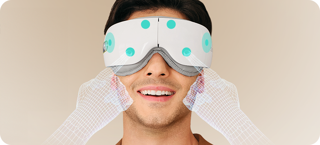 Mężczyzna uśmiecha się, używając białego masażera oczu SKG ES500, z wizualizacją masażu skroni dłońmi