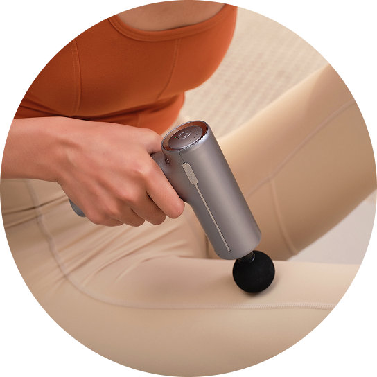Kobieta masuje udo, trzymając w ręce kompaktowy pistolet do masażu SKG F1-Pro w kolorze srebrnym