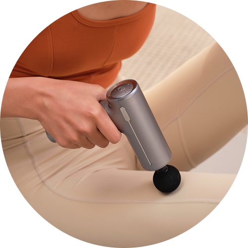 Kobieta masuje udo, trzymając w ręce kompaktowy pistolet do masażu SKG F1-Pro w kolorze srebrnym
