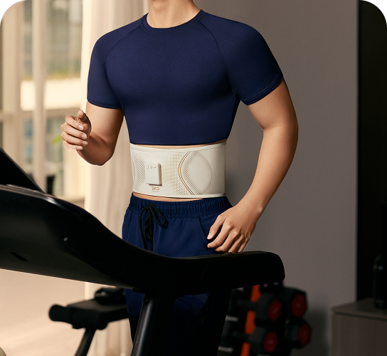 Mężczyzna biegnie na bieżni, używając pasa treningowego SKG GS300 w kolorze beżowym podczas ćwiczeń w domu