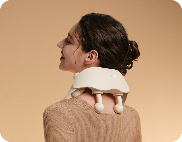 Masażer karku SKG HS500-2 w kolorze beżowym, z dwoma ruchomymi głowicami i paskiem mocującym zaprezentowany na szyi kobiety