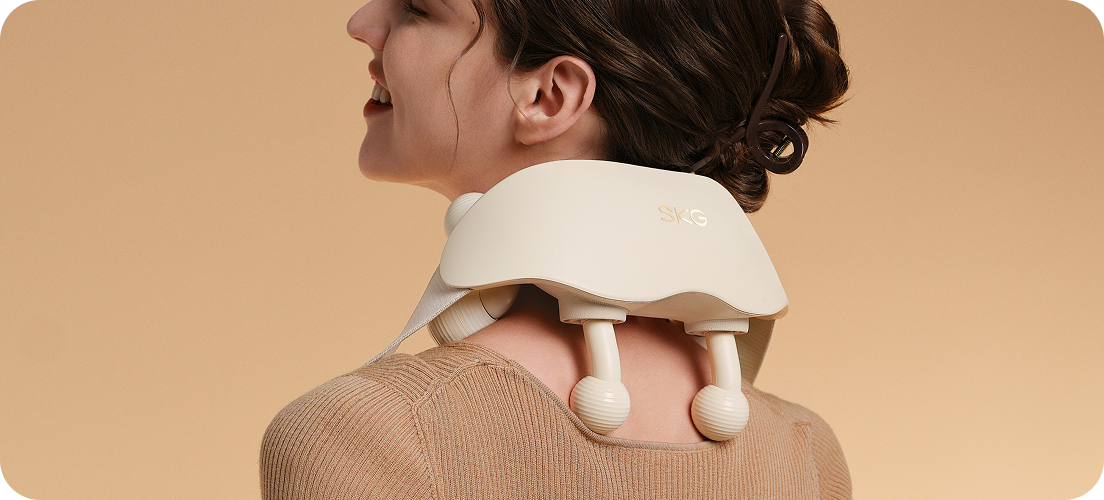 Masażer karku SKG HS500-2 w kolorze beżowym, z dwoma ruchomymi głowicami i paskiem mocującym zaprezentowany na szyi kobiety