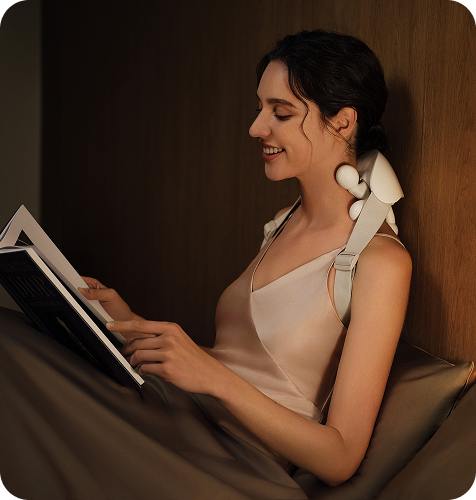 Kobieta w łóżku czyta książkę, używając masażera karku SKG HS500-2 z dwoma ruchomymi głowicami masującymi