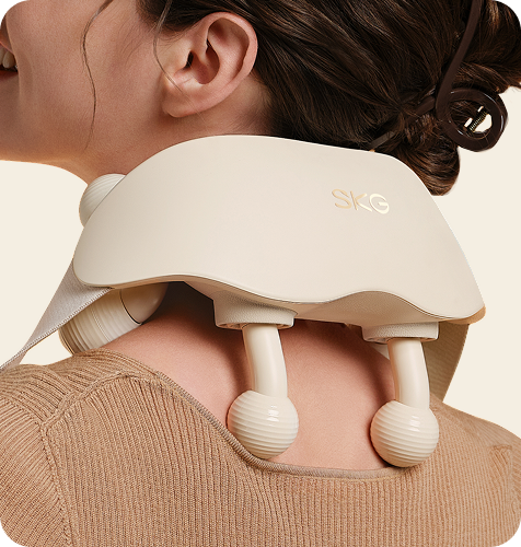 Masażer karku SKG HS500-2 w kolorze beżowym, z dwoma kulistymi głowicami, na karku uśmiechniętej kobiety
