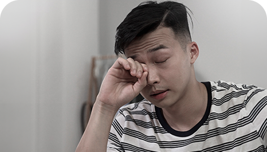 Mężczyzna w koszulce w paski, z zamkniętymi oczami, pociera dłonią powiekę, wyrażając zmęczenie