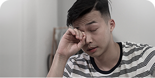 Mężczyzna w koszulce w paski, z zamkniętymi oczami, pociera dłonią powiekę, wyrażając zmęczenie