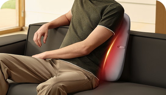 Mężczyzna siedzi na sofie, używając szarego masażera pleców SKG TS700 jako poduszki lędźwiowej