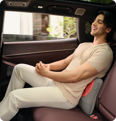 Mężczyzna relaksuje się na tylnym siedzeniu samochodu, używając masażera pleców SKG VS500 z podgrzewaniem