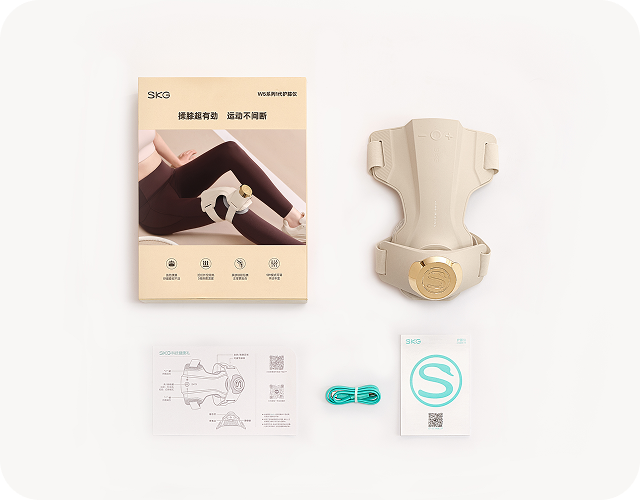 Widok z góry na zestaw masażera kolan SKG WS500: urządzenie, instrukcja, ulotka z logo 'S' i kabel