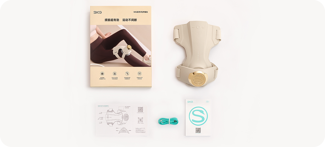 Widok z góry na zestaw masażera kolan SKG WS500: urządzenie, instrukcja, ulotka z logo 'S' i kabel