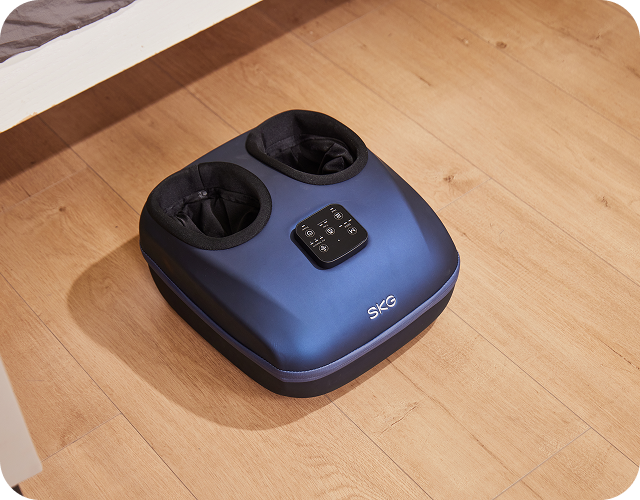 Masażer stóp SKG YS100 w kolorze granatowym, z pilotem na obudowie, leżący na drewnianej podłodze w domu